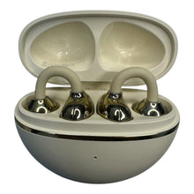 A pair of wireless earbuds in their open charging case, featuring a glossy metallic silver finish with beige silicone ear hooks and a matching beige interior.