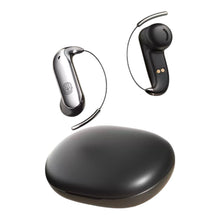Two wireless earbud-style hearing devices with thin wire ear hooks, shown above a glossy black oval charging case on a plain white background.